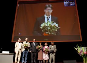 Die Preisverleihung für Nachwuchsforscher in der medizinischen Systembiologie: Jens Timmer (Hepatosys), Preisträger Stefan Lengewie, BMBF-Staatsekretär Helge Braun, Preisträgerin Edda Schulz und das Stifter-Ehepaar Monika und Thomas Zimmermann (MTZ-Stiftung), auf der Leinwand von Boston zugeschaltet: Preisträger Thomas Maiwald.