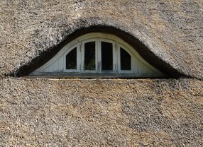 Eigentlich sollen Reetdächer Jahrzehnte lang Wind und Wetter abweisen. Dann werden sie wie auf diesem Bild von einem für Norddeutschland typischen Dachauge zwar grau, die Halme bleiben aber trocken und intakt.